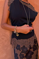 Primo piano del top Black and Chocolate Lace Jersey con bordi in pizzo cioccolato e ciondoli dorati.