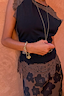 Black jersey top with chocolate lace trim and gold charm jewellery, featuring lace detail at the neckline and hem.