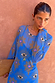 Blue Eye Mesh Dress with eye and heart motifs, long sleeves and a fitted silhouette against a textured wall.