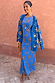 Blue Eye Mesh Maxi Dress with heart and eye motifs, layered with a matching cardigan and tan clutch.