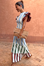 Thumbnail for Blue Stripe Alena Midi Dress featuring tiered striped panels and burgundy ruffle sleeves, paired with a spotted clutch.