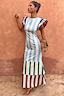Blue Stripe Alena Midi Dress in cotton-linen with burgundy ruffle sleeves and a tiered hem against a terracotta wall.