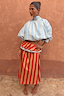 Blue Stripe Batwing Blouse featuring a high neck and shirred cuffs, styled with a red striped skirt.