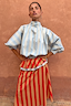 Thumbnail for Blue Stripe Batwing Blouse with voluminous sleeves and high neck, styled with a red striped mini dress.