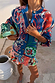 Blue Mari Cardigan featuring orange and turquoise paisley motifs and gold stud details, styled as a wardrobe staple.