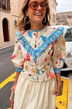 Celestial Nia Top in cream cotton featuring celestial motifs, blue ruffle shoulders and button-up front.