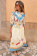 Cream cotton Celestial Nia Top featuring a celestial sun print, blue ruffled shoulders and button-up front.