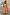 Thumbnail for Check Lola Mid-axi Dress in yellow, pink and orange with a ruched bodice and cotton skirt against a textured wall.