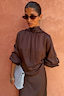 Thumbnail for NFD Chocolate Tie Neck Blouse in satin with volume sleeves and a high neck, styled with a light blue clutch.