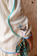 Cream Celestial Martha Cardigan sleeve featuring embroidered cosmic motifs and blue blanket stitch trim.