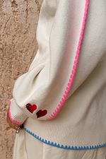 Cream Celestial Martha Cardigan detail highlighting the pink scalloped trim, red hearts and blue contrast hem.