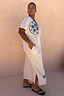 Cream cotton Dolce Vita T-Shirt Dress with blue sun motifs and side pockets, shown on a model in size XL.