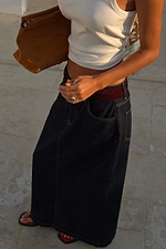 Dark blue denim pencil skirt in a midi silhouette, styled with a white vest and tan suede handbag.
