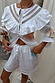 White cotton Dreamer Willa Top featuring sun and star motifs, a ruffled cutout neckline and flared cuffs.