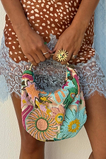 Dreamer Bag with multicoloured glass bead embroidery, sun motifs and a metal bar handle, held by a model.