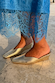 Metallic Gold Wedge Mule with a pointed toe and sculpted heel, paired with a blue lace dress.