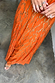 Orange Jacquard Bibi Dress with gold metallic threads and a full skirt, paired with leopard print sandals.