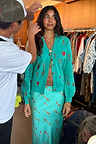 Turquoise Key Dorris Skirt and matching cardigan with a gold key print, styled on a model on set.