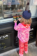 Kids Red and Pink Bandana Knitted Set featuring a paisley print jumper and trousers, worn by a child at a shop window.