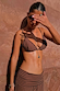 Ribbed chocolate and black stripe bra top and matching trousers on a model against a textured wall.