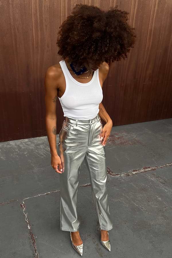 Metallic Silver Vegan Leather Trousers styled with a white tank top and matching pointed heels for a street style look.