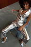 Silver Vegan Leather Trousers and matching metallic waistcoat worn by a model sitting on a chair.