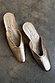 Metallic Gold Wedge Mules with a pointed toe and sculpted heel, featuring a signature graphic on the inner sole.