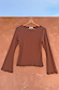 Ribbed Chocolate Stripe Top with flared bell sleeves hanging on a wooden hanger against a terracotta wall.