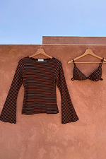 Ribbed chocolate stripe top with flared sleeves and matching bra set hanging against a terracotta wall.