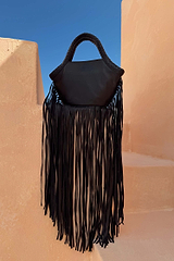 Black Leather Fringe Bag with a plaited handle and long fringe detail against a terracotta wall.