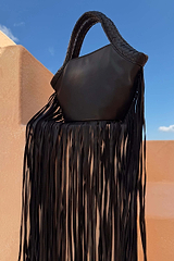 Black Leather Fringe Bag featuring a plaited handle and long fringe, displayed outdoors against a blue sky.