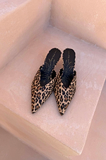 Leopard Heel Mules with a pointed toe and V-cut detail in an iconic animal print, displayed on neutral stone steps.