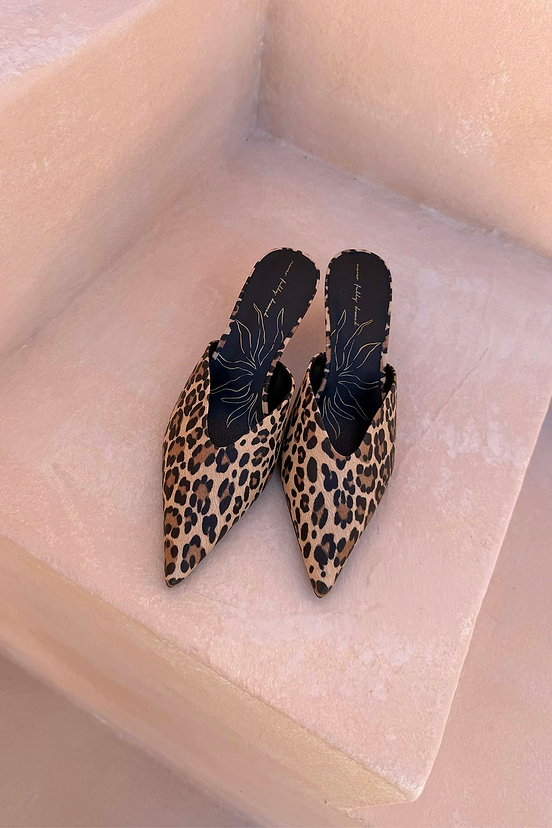 Leopard Heel Mules with a pointed toe and V-cut detail in an iconic animal print, displayed on neutral stone steps.