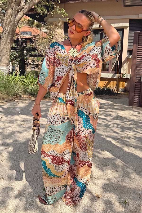 Wide-leg Morocco Trousers in a celestial patchwork print, paired with a matching tie-front top for a vacation look.