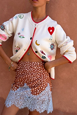 Morocco Charms Cheryl Cardigan in cream with red trim and iconic motifs, paired with a leopard print lace-hem skirt.