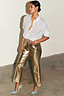 Metallic gold vegan leather trousers styled with a white shirt and light blue pointed heels on a model.