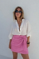 Iconic Pink Vegan Leather Mini Jaspre Skirt styled with a white shirt and dark sunglasses.