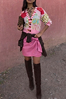 Iconic Pink Vegan Leather Mini Jaspre Skirt styled with a patterned cardigan and brown knee-high boots.