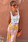 Pink Fawn Poppy Midi Maeva Skirt with yellow floral motifs, styled with a white ribbed tank top and sunglasses.