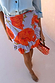 Thumbnail for Blue Poppy Mini Jaspre Skirt featuring a bold orange poppy print and frill hem, styled with a beaded bag.