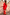 Thumbnail for Red Celestial Dorris Skirt in red satin with sun and hand motifs, styled with a red knit jumper against a stone wall.