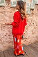 Red Celestial Dorris Skirt in red satin with sun and hand motifs, styled with a red knit jumper against a stone wall.