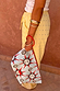 Detachable sun print pouch with a red wristlet strap, paired with yellow striped trousers for vacation styling.