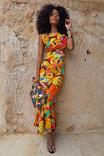 Rio A-Symmetric Skirt in tropical fruit print, styled as a co-ord set against a textured stone wall.