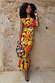 Rio A-Symmetric Skirt in tropical fruit print, styled as a co-ord set against a textured stone wall.