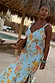 Sky Blue Floral Sofia Dress with tie knot shoulders and bias-cut fabric on a model in a resort setting.