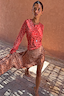 Thumbnail for Spliced Fawn Mini Nola Tie Dress in a red and brown spotted print with long sleeves and a flared hem.