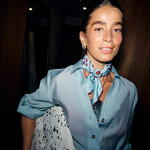 Blue and red Bingo Bandana with lips motifs, tied around the neck of a model wearing a light blue shirt.