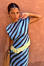 NFD blue, navy and cream stripe asymmetrical top with yellow lace trim, styled against a textured terracotta wall.