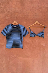 Blue Stripe Bra Baby T-Shirt with a detachable bra overlay, hanging on wooden hangers against a textured wall.